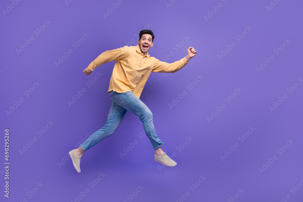 Full body photo of nice young male running hurry fast excited dressed stylish yellow outfit isolated on purple color background