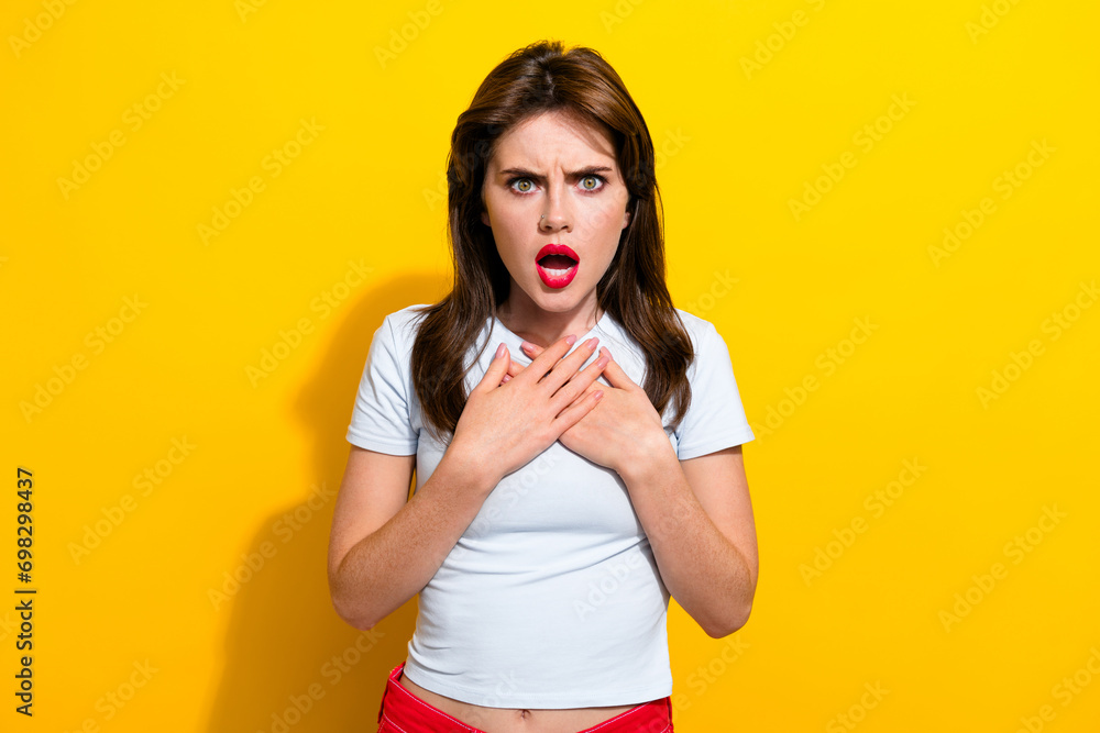 Portrait of offended abused girl red lips wear white t-shirt hold hands on chest astonished staring isolated on yellow color background - obrazy, fototapety, plakaty 