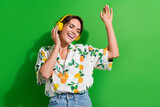 Photo attractive energetic young girl dj listening new release spotify mix music test orange headphones isolated on green color background