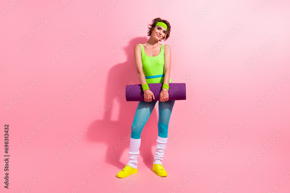 Full size photo of pretty positive fitness instructor girl hands hold fitness carpet isolated on pink color background