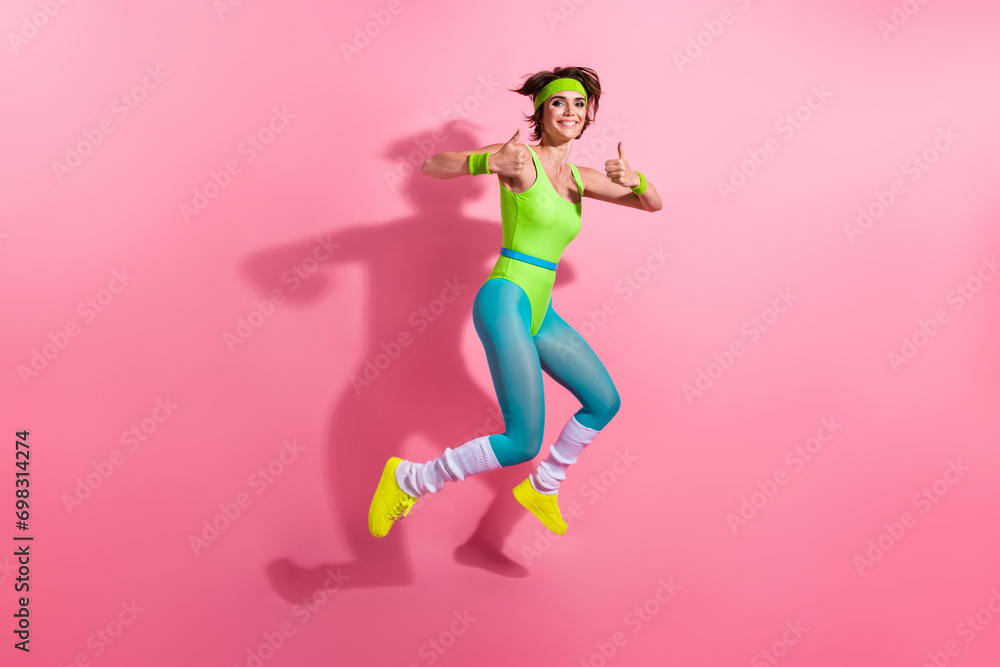 Full body profile portrait of motivated sporty lady jumping demonstrate thumb up approve isolated on pink color background