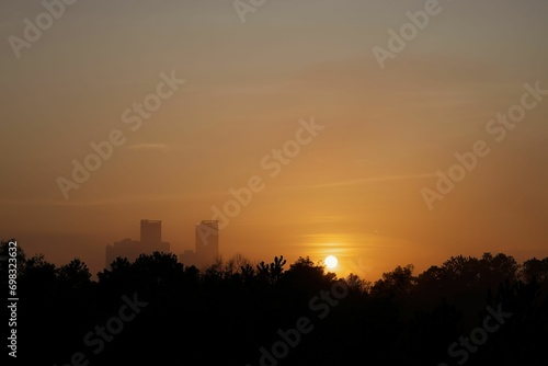 Golden sunrise in the vicinity of the tall building. trees in silhouette.