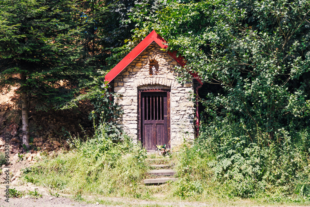 A small chapel in a summer forest among greenery. A small chapel in a summer forest among greenery.