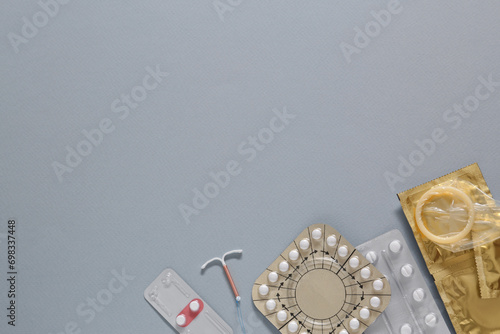Fototapeta Naklejka Na Ścianę i Meble -  Contraceptive pills, condoms and intrauterine device on gray background, flat lay with space for text. Different birth control methods