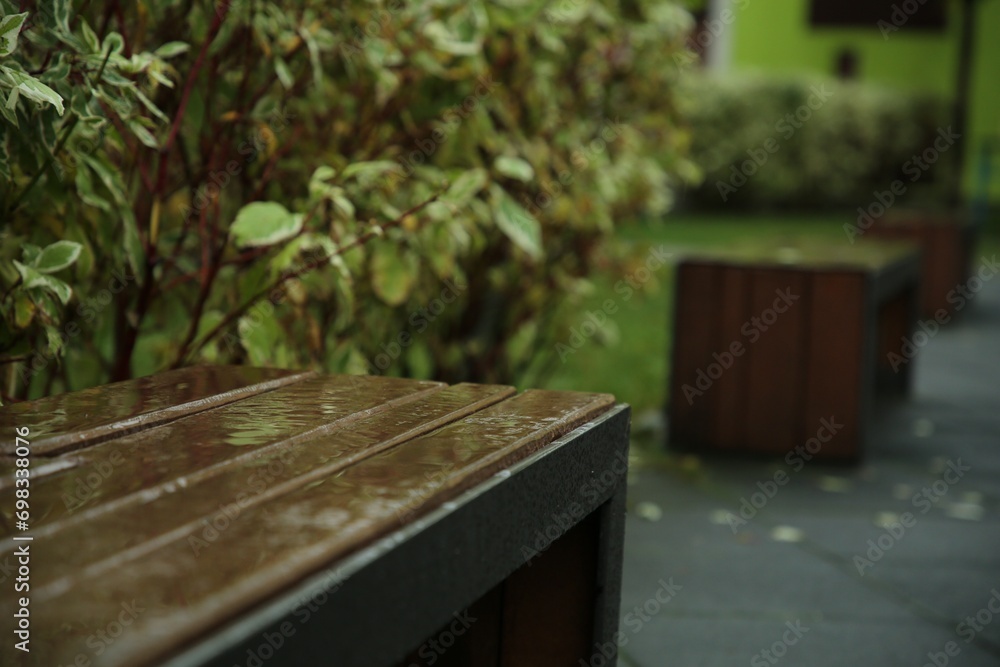 Wet wooden bench on city street after rain, space for text Wet wooden bench on city street after rain, space for text