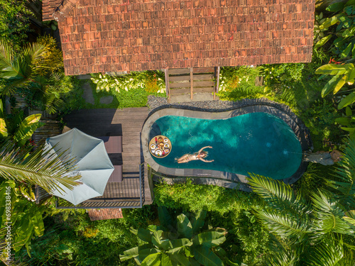 Aerial view of a young woman relaxing in a swimming pool, rural Bali © Goran