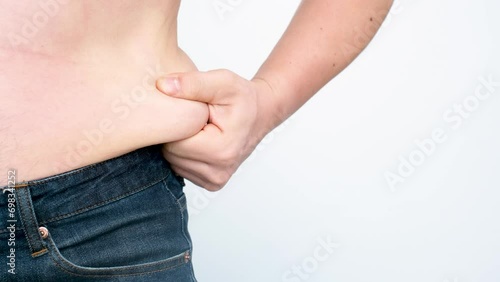 A male hand holding excessive belly fat on white background, overweight concept. photo