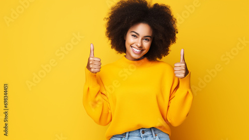 Happy African American woman giving thumbs up on a solid background photo