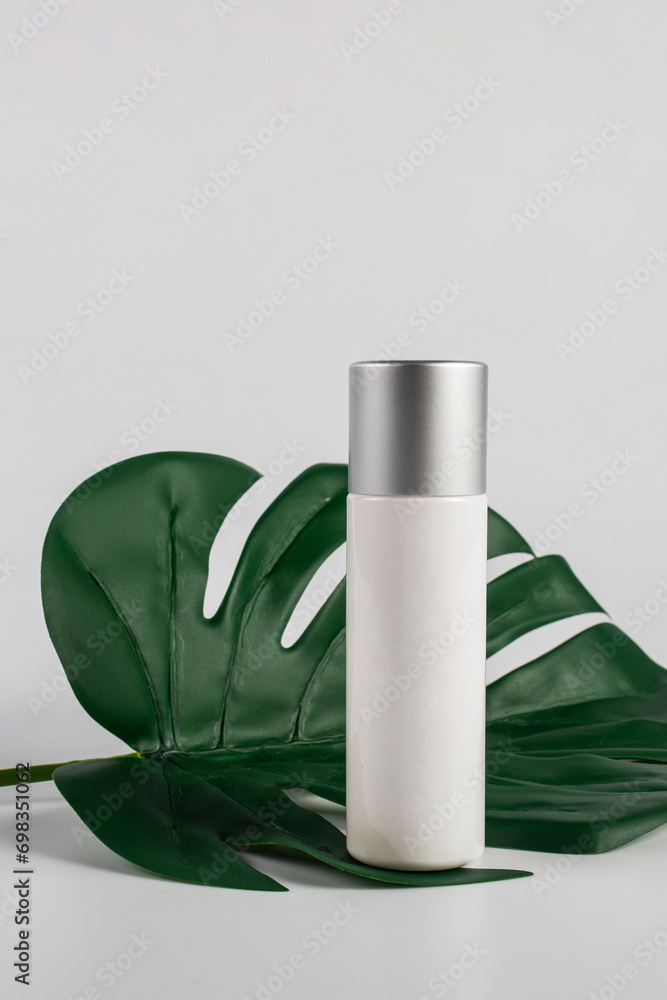 Cosmetic product in tube, bottle, lotion or serum on white background and tropical monstera leaves. Cosmetic product in tube, bottle, lotion or serum on white background and tropical monstera leaves.