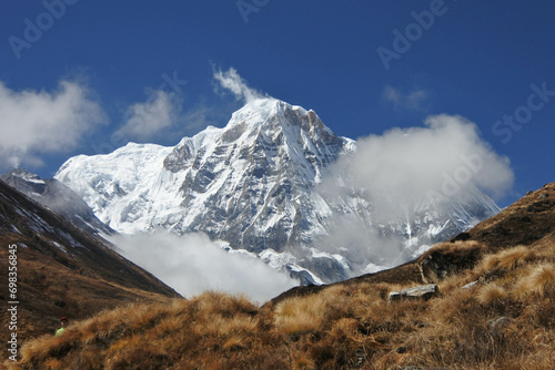 Stunning views of snow mountains, blue skies and large rocks along the track to Annapurna Base Camp.