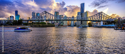 Brisbane city skyline at dusk with Storey Bridge and ferry in foreground