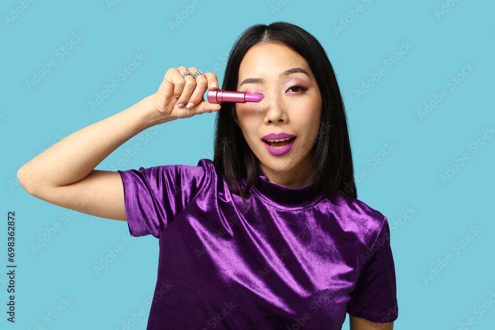 Beautiful Asian woman with lipstick on blue background Beautiful Asian woman with lipstick on blue background