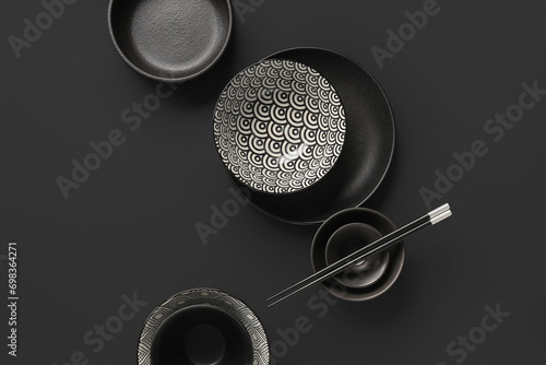 Bowls with chopsticks on black background. Chinese table setting photo