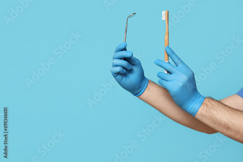 Dentist hands with toothbrush and dental mirror on blue background. World Dentist Day photo