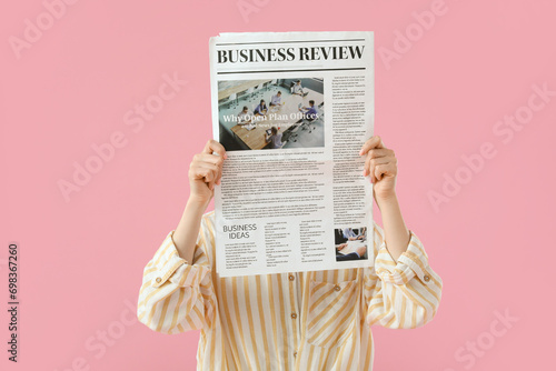 Young woman with newspaper on pink background photo