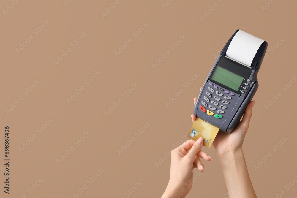 Woman with credit card and payment terminal on brown background Woman with credit card and payment terminal on brown background