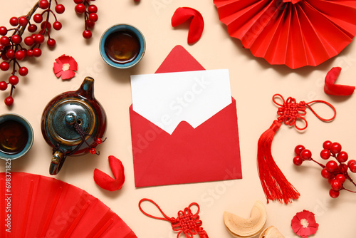 Envelope with blank card, fortune cookies, teapot and Chinese symbols on beige background. New Year celebration photo