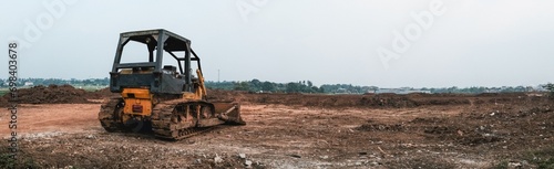 Panoramic view of old rusted metal yellow tractor bulldozer in dry open field. © igunawan.photo