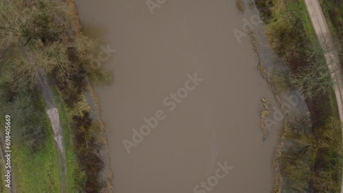 Aerial birdseye view of high water in springtime, Barta river (Latvia) flood, brown and muddy water, overcast day, wide drone shot moving forward photo