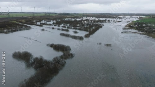 Aerial establishing view of high water in springtime, Alande river (Latvia) flood, brown and muddy water, agricultural fields under the water, overcast day, wide drone shot moving forward photo