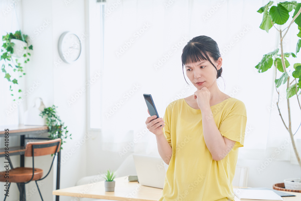スマートフォンを操作する自宅で仕事をする女性 立ちポーズ スマートフォンを操作する自宅で仕事をする女性 立ちポーズ