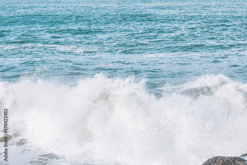 Wave splashes close-up. Crystal clear sea water hitting rock formations in the ocean in San Francisco Bay, blue water, pastel colors.