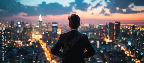 Confident businessman admiring cityscape from rooftop at twilight. photo