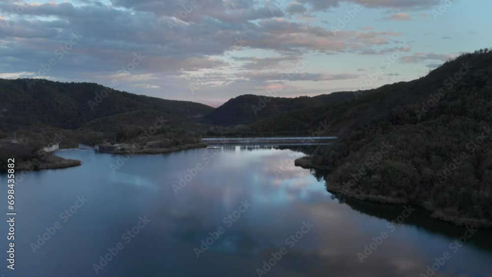 Aerial orbit over mountain lake with a dam colorful sunset colors forest trees Aerial orbit over mountain lake with a dam colorful sunset colors forest trees