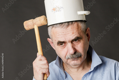 A crazy man with a saucepan on his head tries to find a thought with a hammer. photo