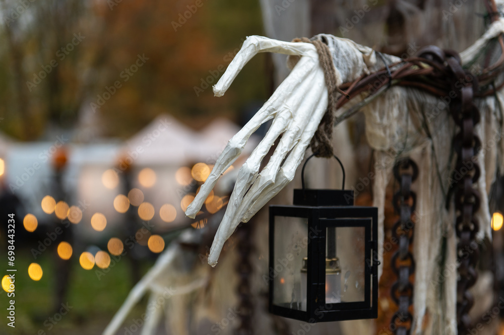 Halloween ghost hand with lantern on blurred bokeh background