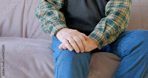 Senior man retirement knee joint pain on sofa.