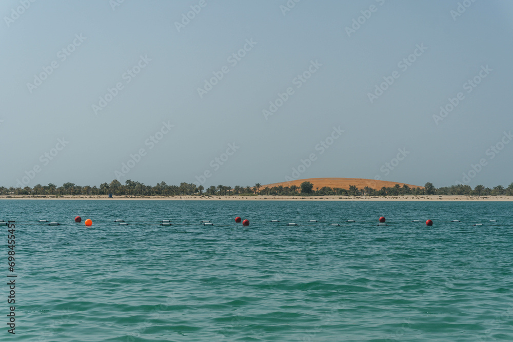 very warm sea water in arabian golf arabic with palm trees desert island at horizon swimming are in abu dhabi