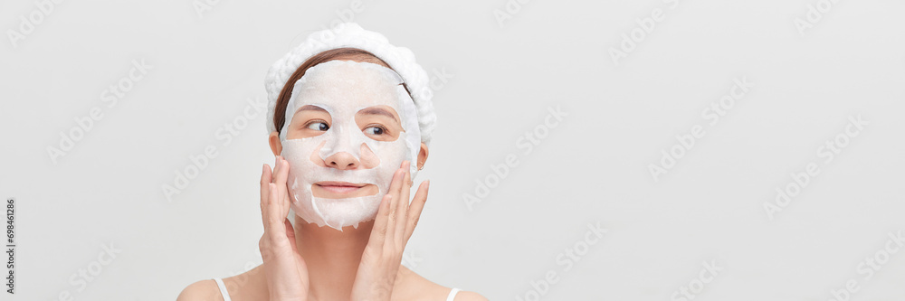 Woman with a cloth moisturizing mask on her face isolated on white banner background