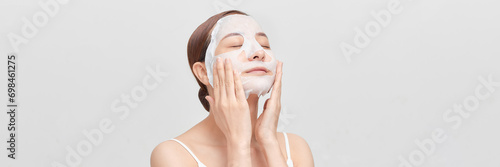 Banner of beautiful young woman applying rejuvenation facial mask on her face photo