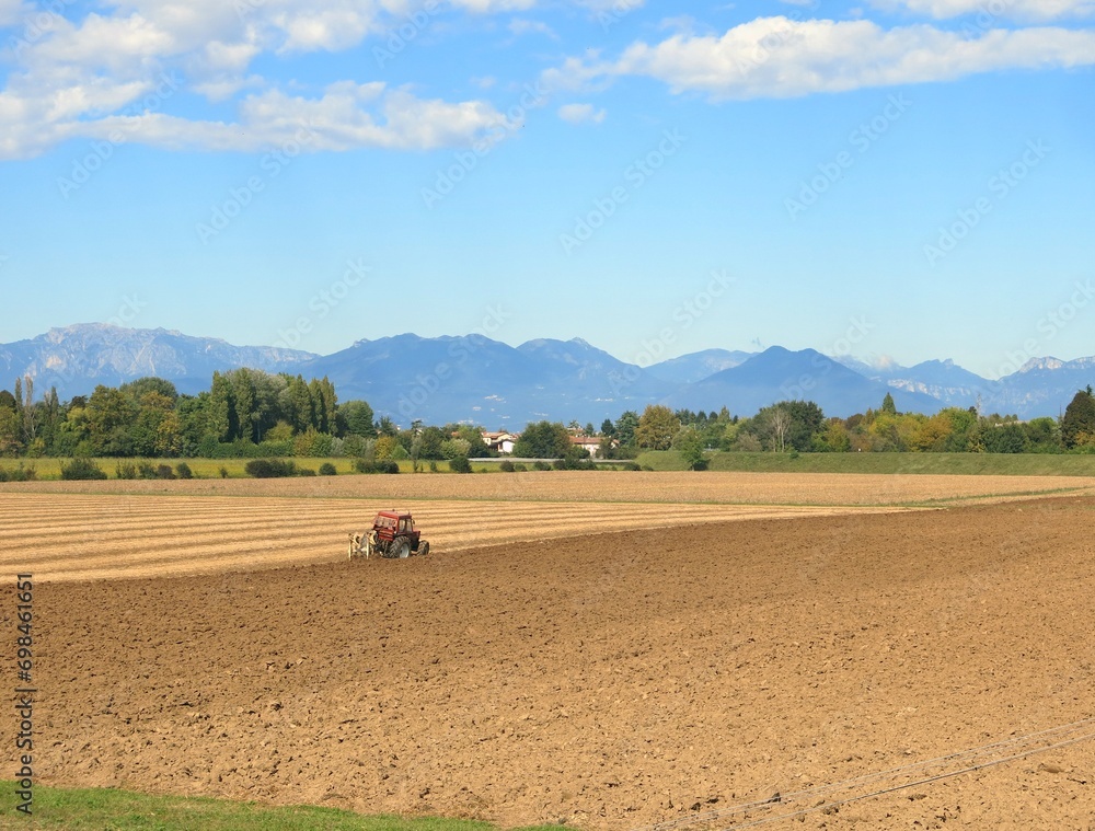 Obraz premium tractor in the middle of the plow field during the sowing period in the Po Valley in Italy