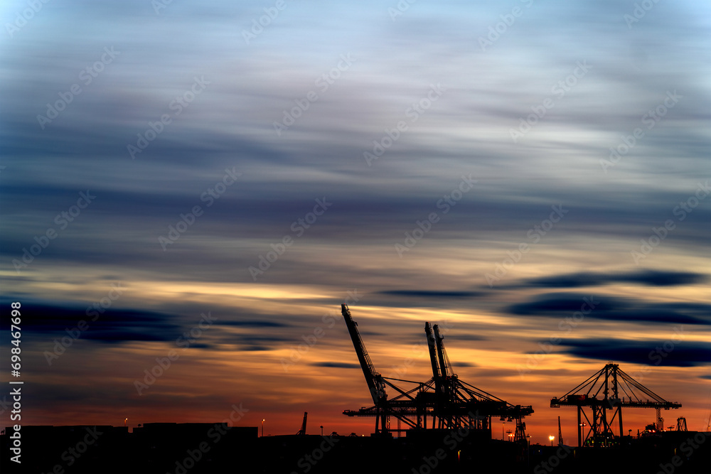 Long Exposure of Commercial Dock Silhouette Under Orange-Blue Dusk Sky