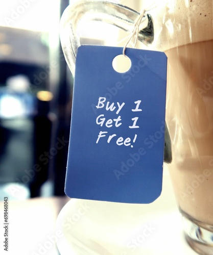 Blue tag hanging on coffee cup with text written BUY 1 GET 1 FREE, common form of sales promotion- deal involves offering a second product for the first price to attract customers