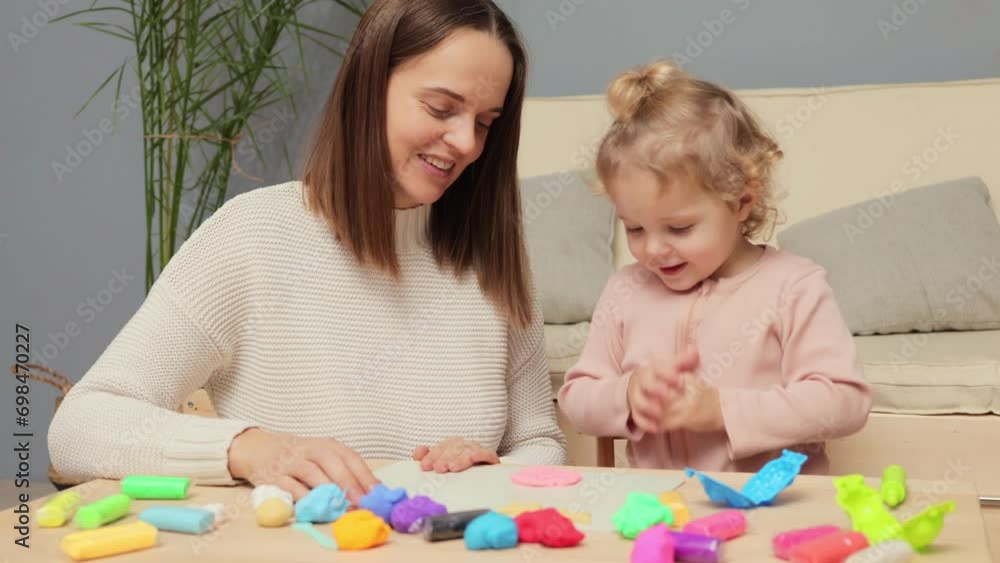 Modeling with children. Hands-on creativity. Playful plasticine activity. Happy positive Caucasian kid girl and mother playing colorful clay plasticine together in home interior Modeling with children. Hands-on creativity. Playful plasticine activity. Happy positive Caucasian kid girl and mother playing colorful clay plasticine together in home interior