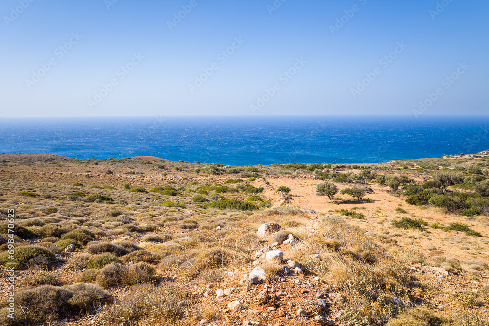 The arid rocky coast and its green countryside, in Europe, Greece, Crete, towards Matala, By the Mediterranean Sea, in summer, on a sunny day.