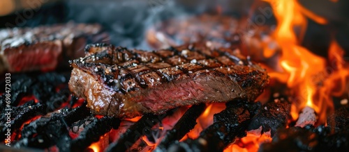 Cooking a New York beef steak on a grill with hot coals and smoke.
