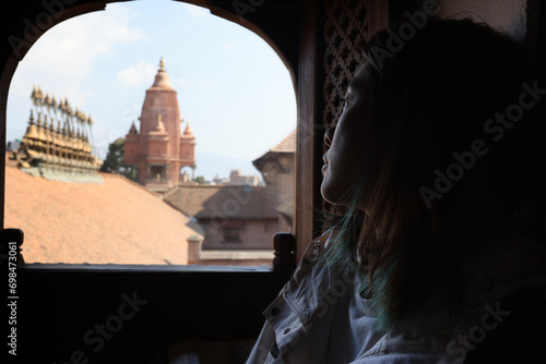 girl watch outside though Newar window window having the view of temple of Silu Mahadeva in Bhaktapur durbar square photo