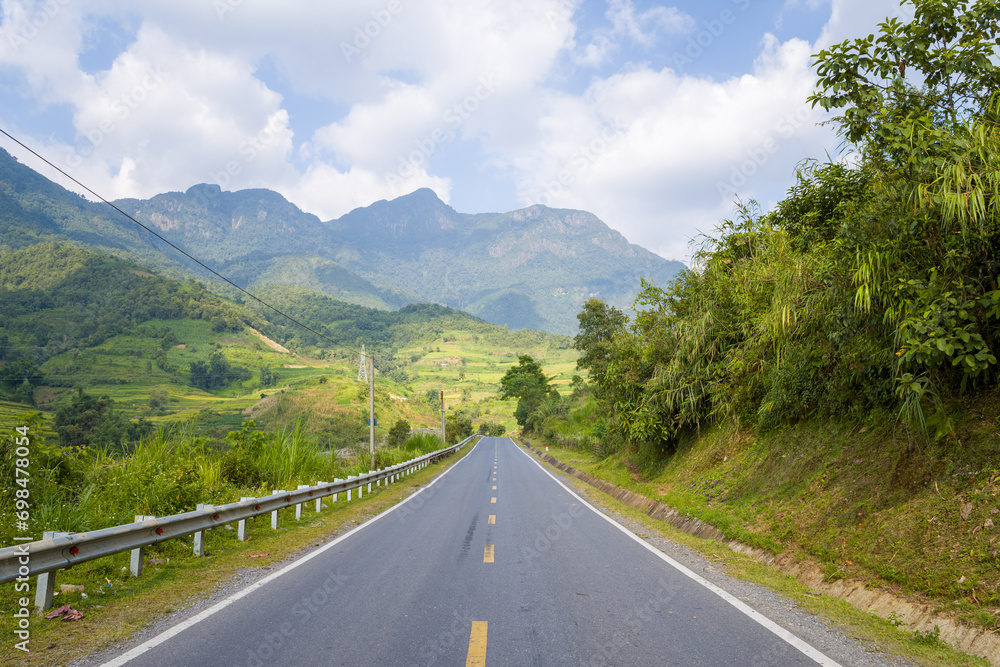 An asphalt road in the middle of the countryside and mountains, in Asia, Vietnam, Tonkin, between Lai Chau and Sapa, in summer, on a sunny day.