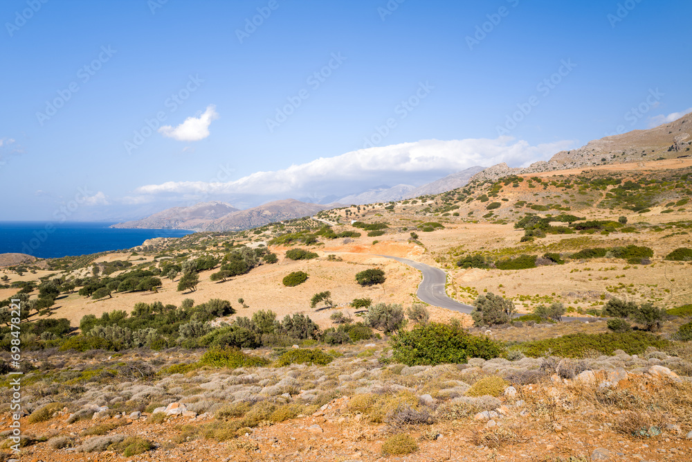 The arid rocky coast and its green countryside, in Europe, Greece, Crete, towards Matala, By the Mediterranean Sea, in summer, on a sunny day.