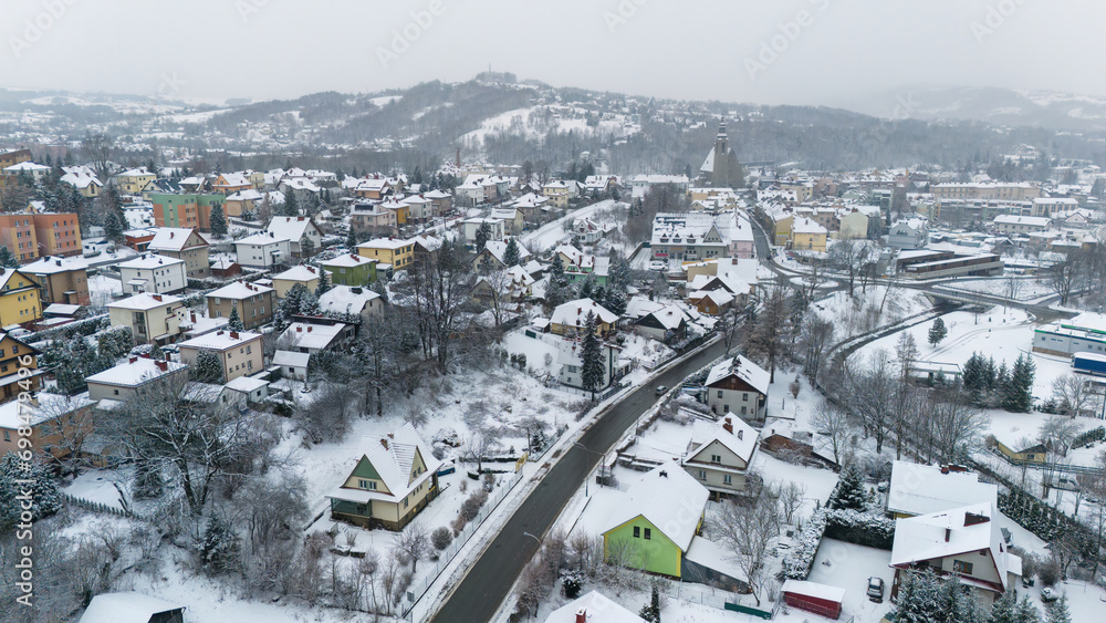 Drone shot of a small town named Limanowa in mountains in Poland covered with fog and snow