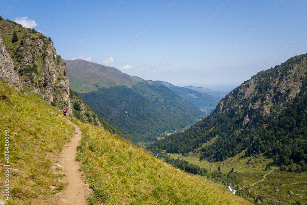 A hiking path in the green countryside , in Europe, in France, Occitanie, in the Hautes-Pyrenees, in summer, on a sunny day.