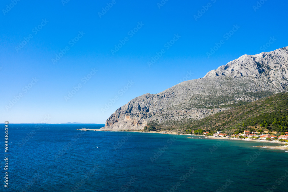 The town on the rocky coast in the middle of green countryside , Europe, Greece, Aetolia Acarnania, Kato Vasiliki towards Patras, by the Ionian Sea, in summer on a sunny day.