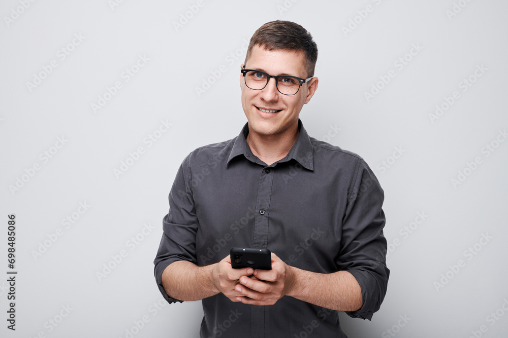 Portrait of young businessman holding mobile phone in hand with happy smiling face. Person with smartphone isolated on white background. Portrait of young businessman holding mobile phone in hand with happy smiling face. Person with smartphone isolated on white background.