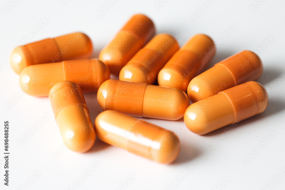 Medicine background. Orange pills isolated on white. Pile of capsules. Tablets background. Vibrant vivid color drugs. Antibiotics background. Medicine background. Orange pills isolated on white. Pile of capsules. Tablets background. Vibrant vivid color drugs. Antibiotics background.