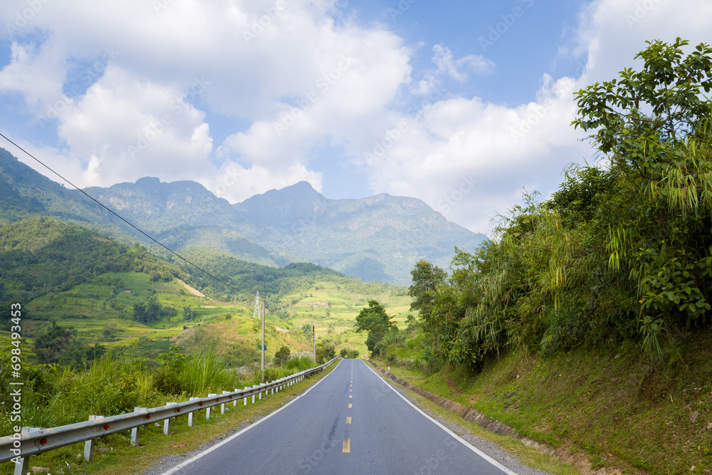 An asphalt road in the middle of the countryside and mountains, in Asia, Vietnam, Tonkin, between Lai Chau and Sapa, in summer, on a sunny day.