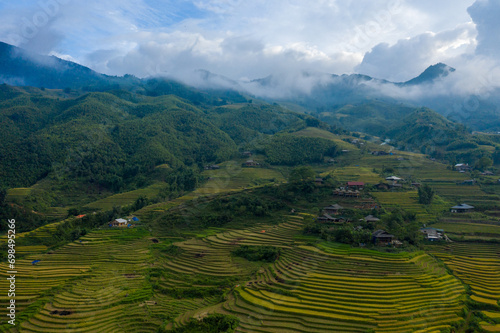 The green and yellow rice terraces at the foot of the green mountains, in Asia, Vietnam, Tonkin, Sapa, towards Lao Cai, in summer, on a sunny day. photo